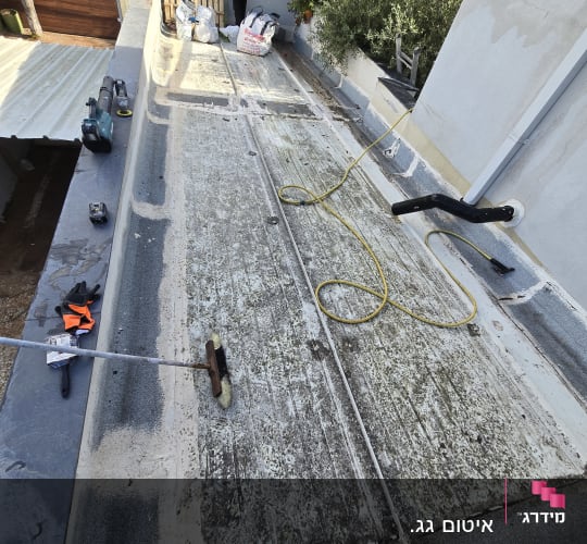 גג עם כלים וחומרים לאיטום, כולל מברשת וכבלים